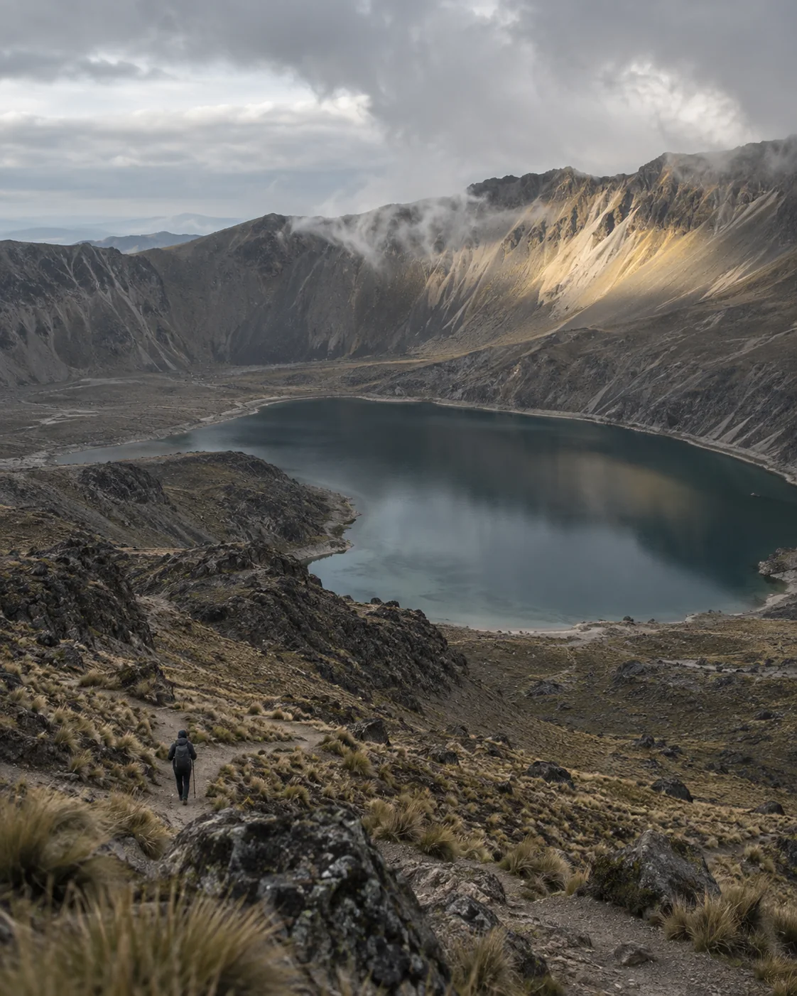 Vista cinematográfica conceptual del cráter del Nevado de Toluca con una persona descendiendo hacia la laguna
