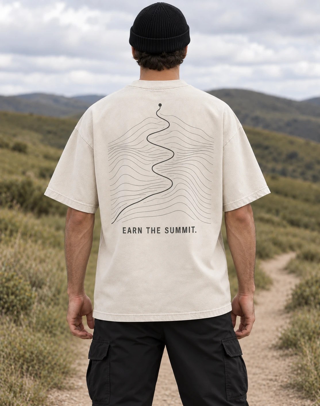 Persona usando la playera heavyweight Earn the Summit en un sendero volcánico